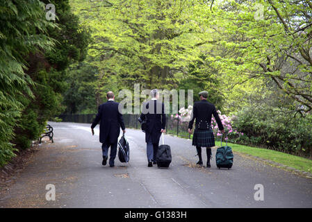 Drei Hochzeitsgäste auf der Straße im Kelvingrove Park Glasgow,Scotland,U.K passendes Gewand. Stockfoto