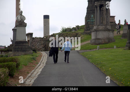 Mann und Frau gehen Hand in Hand steht jeweils vor Grab Stein in der Nekropole von Glasgow, Schottland, Großbritannien Stockfoto