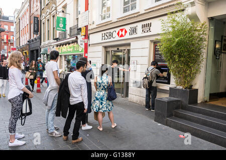 Personen, die vor dem HSBC-Geldautomaten in der Gerrard Street, Soho, London, WC2, England, Schlange stehen, VEREINIGTES KÖNIGREICH Stockfoto