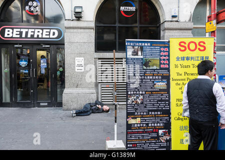 Einem Obdachlosen Mann schlafen draußen BETFRED auf Gerrard Street in Londons Chinatown Bereich. Stockfoto