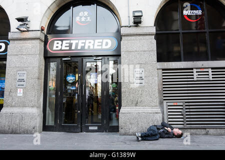 Einem Obdachlosen Mann schlafen draußen BETFRED auf Gerrard Street in Londons Chinatown Bereich. Stockfoto