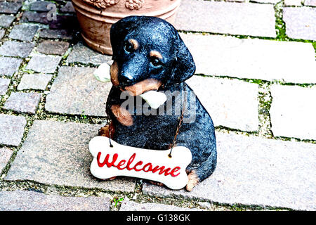 Ein kleiner Hund als Fihure aus Steingut, trägt ein Schild "Willkommen" Stockfoto