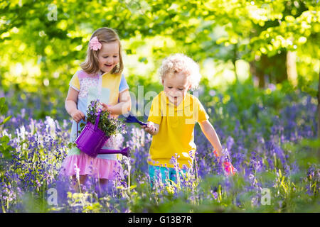 Kinder im Garten. Kinder spielen im Freien in Glockenblumen Wiese. Kleine Mädchen und jungen, Bruder und Schwester, im Garten arbeiten Stockfoto