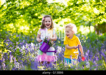 Kinder im Garten. Kinder spielen im Freien in Glockenblumen Wiese. Kleine Mädchen und jungen, Bruder und Schwester, im Garten arbeiten Stockfoto