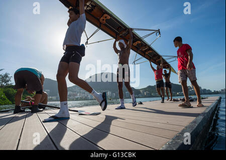 RIO DE JANEIRO - 22. März 2016: Brasilianische Ruderer tragen ihr Boot zurück zum Clubhaus am Logoa Rodrigo de Freitas-Lagune. Stockfoto