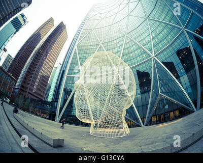 Ein Fischauge Blick auf die Skulptur Wonderland von Jaume Plensa vor The Bow Wolkenkratzer in Calgary, Alberta, Kanada. Stockfoto