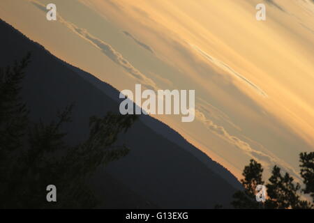 Himmel mit verschiedenen Schattierungen von Orange über ein Bergsilhouette in Schweden in ungewöhnlichen Blickwinkel. Stockfoto