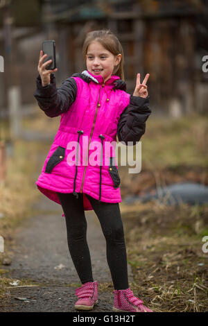 Kleines Mädchen macht Selfie am Telefon, im Freien. Stockfoto