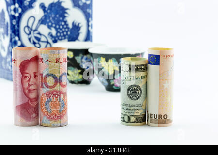 Chinesische Yuan Währung, amerikanisches Geld und Europäische Union Euro stehen vor asiatische Porzellan Teetassen und Vorratsgefäß Stockfoto