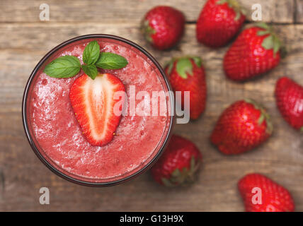 Smoothie mit Erdbeeren in ein Glas, frischen Erdbeere auf alten hölzernen Hintergrund (Draufsicht) Stockfoto