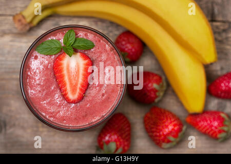 Smoothie mit Banane und Erdbeere im Glas, frische Erdbeeren und Bananen auf den alten hölzernen Hintergrund Stockfoto
