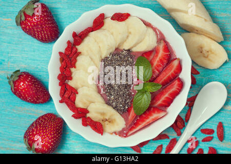 Ernährung, gesundes Frühstück. Beeren-Smoothie in einer Schüssel mit einer Banane, Gojibeeren, Erdbeeren und Chia-Samen Stockfoto