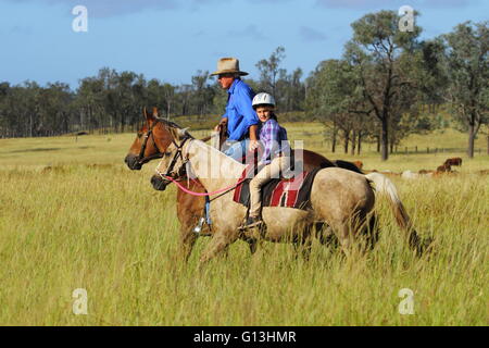 Ein Großvater und junge Enkelin Reitpferde auf einem Vieh-Grundstück in der Nähe von Eidsvold in Queensland, Australien. Stockfoto