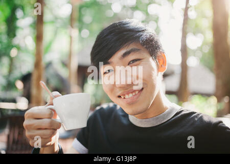 Ein Mann am Morgen im hellen Sonnenschein Kaffee trinken. Stockfoto