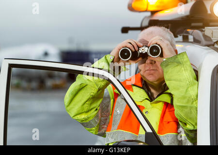 Bodenpersonal auf Start-und Landebahn am Flughafen Glasgow mit Landescheinwerfer im Hintergrund Stockfoto