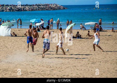 Unbekannte Menschen spielen Fußball am Strand. Fußball ist ein sehr beliebter Sport in Marokko. Stockfoto