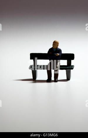 Miniatur-Modell eines älteren Mannes sitzen auf einer Bank Stockfoto