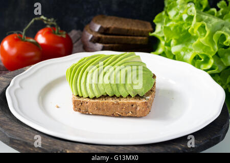 Frisch geschnittene Avocado auf Vollkornbrot auf weißen Teller Stockfoto