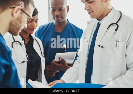 Gemischtrassig Ärzteteam steht lesen Patientenakten auf einer Visite in einem Krankenhaus, Nahaufnahme von verschiedenen Männern und wom Stockfoto