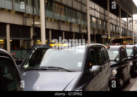 Eine Warteschlange von schwarzen Londoner Taxis in einer Reihe an einem Taxistand, warten bis die Passagiere in der Nähe von Kings Cross Station mit Schwimmbad Licht pick beleuchtet Stockfoto