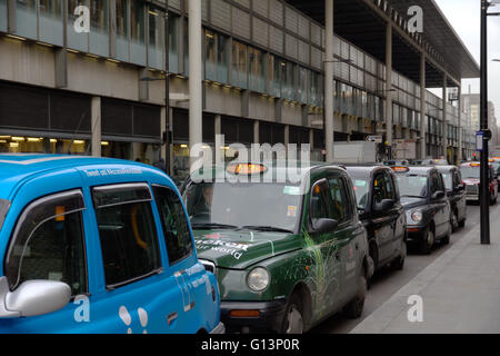 Eine Warteschlange von schwarzen Londoner Taxis in einer Reihe an einem Taxistand, warten bis die Passagiere in der Nähe von Kings Cross Station mit Schwimmbad Licht pick beleuchtet Stockfoto