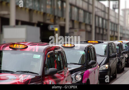 Eine Warteschlange von schwarzen Londoner Taxis in einer Reihe an einem Taxistand, warten bis die Passagiere in der Nähe von Kings Cross Station mit Schwimmbad Licht pick beleuchtet Stockfoto