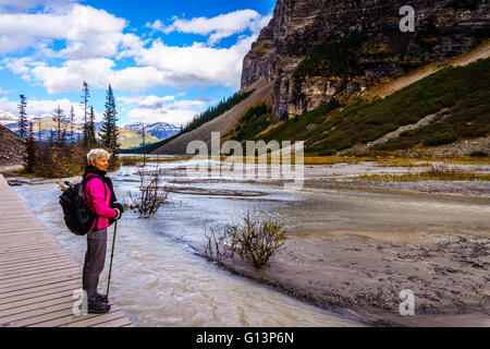 Ältere Frau genießt die Aussicht der Welt berühmten Lake Louise und die umliegenden Berge in den Rocky Mountains in Kanada Stockfoto