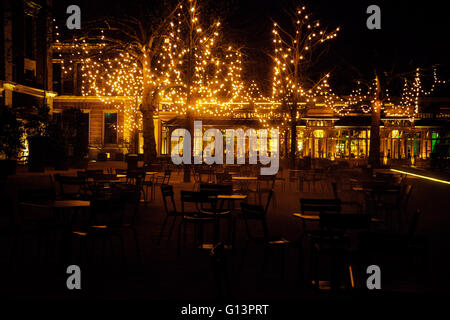 leere Nacht Restaurant, viele Tische und Stühle mit niemand, magische Lichterketten an Bäumen wie Weihnachten Stockfoto