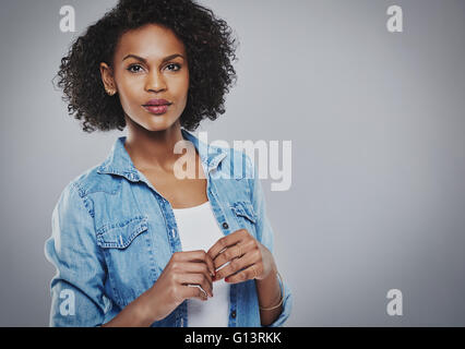 Betroffenen Frau mit blauen Jeans Shirt hält die Hände zusammen vor ihr auf grauem Hintergrund Stockfoto