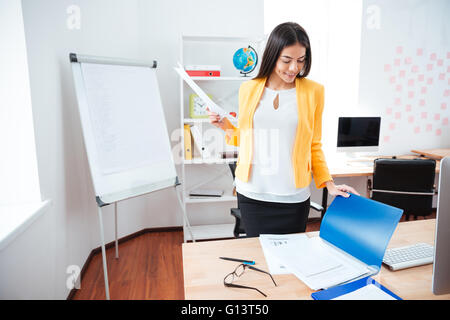 Glücklich Geschäftsfrau mit Papieren im Büro arbeiten Stockfoto