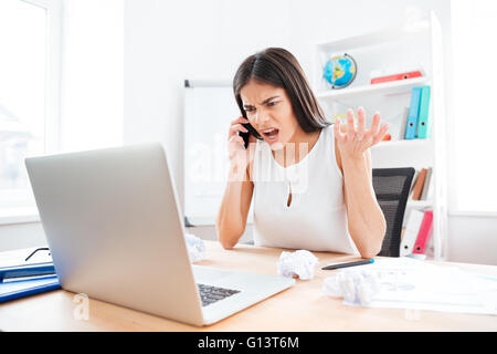 Wütend Geschäftsfrau telefonieren im Büro Stockfoto