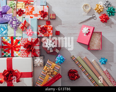 Geschenk-Boxen auf dem Schreibtisch mit Papier umwickeln rollt, Bänder und Schere, feiern und Weihnachten-Konzept Stockfoto