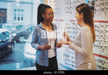 Afrikanische amerikanische Frau in ein optometriker Store in den Kauf von ein paar Frames für ihre Brille unterstützt werden Stockfoto