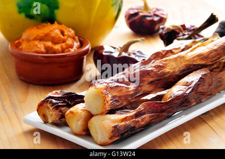 Nahaufnahme einer Platte gegrillte Calcots, katalanische süßen Zwiebeln und eine Schüssel mit Romesco-sauce Stockfoto