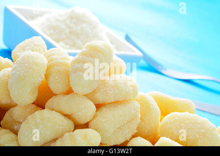 Nahaufnahme von einem Haufen von Gnocchi und eine Schüssel mit geriebenem Parmesan auf einem Tisch Stockfoto