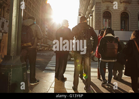 Menge von New Yorkern, die darauf warten, überqueren Sie die 6th Avenue und die aufgehende Sonne während der Hauptverkehrszeit East 34th Straße betreten Stockfoto