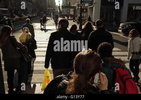 Menge von New Yorkern, die darauf warten, überqueren Sie die 6th Avenue und die aufgehende Sonne während der Hauptverkehrszeit East 34th Straße betreten Stockfoto