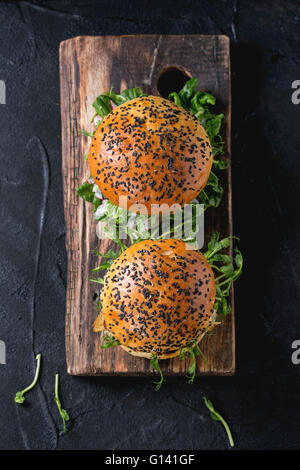 Hausgemachte traditionelle und Veggie Burger mit Rindfleisch, gebratenen Zwiebeln, süße Kartoffeln, Radieschen und Erbsen-Sprossen, diente über Holz Textur Stockfoto