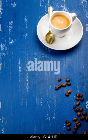 Tasse Espressokaffee und Bohnen auf blau lackierten Holztisch Hintergrund. Draufsicht, vertikale Stockfoto