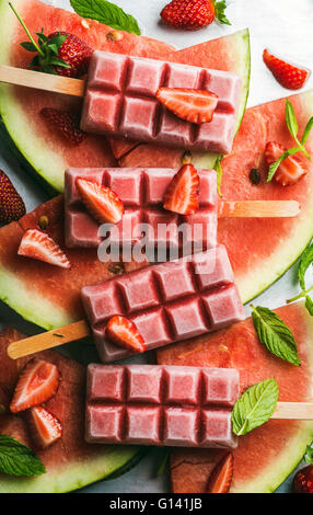 Erdbeer-Wassermelone Eis Eis am Stiel mit Minze über Stahl Fach Hintergrund. Draufsicht, vertikale Stockfoto