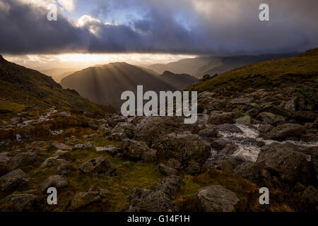 Englischen Lake District, brechen Sonnenstrahlen, wenn die Wolken über Lingmoor fiel, scheut Ghyll im Vordergrund. Stockfoto