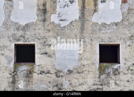 Zwei schreckliche kleine Fenster und Schimmel an der feuchten Wand Stockfoto