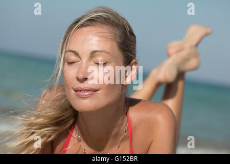 Nahaufnahme des Lächelns blonde enge Augen Frau liegt auf dem sand Stockfoto