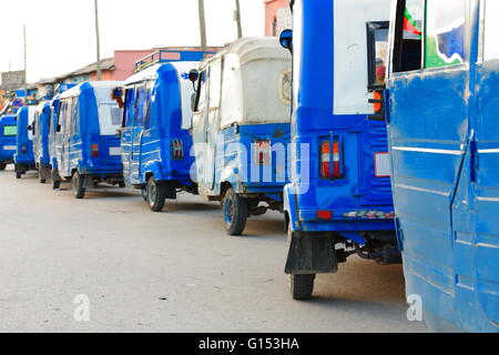 Reihe von weiß und blau lackiert lokale Auto Rikscha-Tuk Tuk-Baby Taxi-Mototaxis auf einer Straße in Zentraläthiopien Mek'ele stationiert. Stockfoto