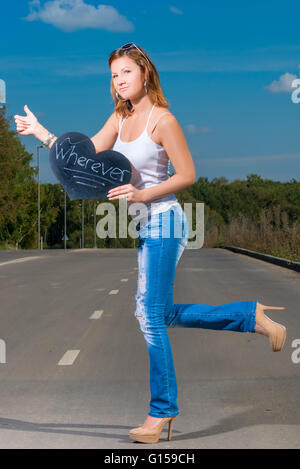 Frau in Jeans und T-shirt, 30 Jahre alt Reisen per Anhalter Stockfoto