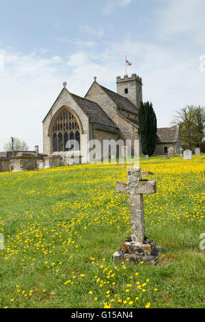 Kreuz Grabstein und Butterblumen vor Str. Marys Kirche, Swinbrook, Oxfordshire, England Stockfoto