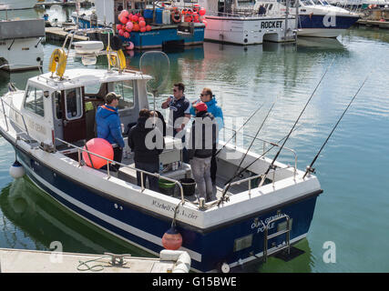 Fünf Männer in einem Fischerboot, Vorbereitung für eine Reise von Poole Quay, Dorset, Großbritannien Stockfoto