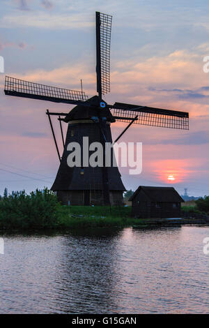 Blauer Himmel und rosa Wolken auf die Windmühle spiegelt sich in den Kanal im Morgengrauen, Kinderdijk, Rotterdam, Zuid-Holland, Niederlande Stockfoto