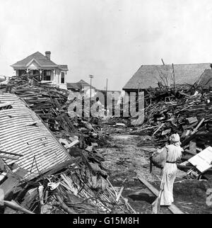 Eine Frau geht durch einen geöffneten Gang in den Trümmern, North auf 19. Street, Galveston, Texas den Hurrikan von 1900 machte Landfall auf der Stadt Galveston, Texas, am 8. September 1900. Es hatte Winde von 145 Meilen pro Stunde am Landfall, so dass es geschätzt. Stockfoto