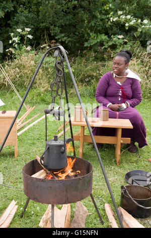 Tewkesbury, UK-17. Juli 2015: Reenactor saß durch einen Brand im Living History Camp am 17. Juli 2015 bei Tewkesbury Mittelalterfest Stockfoto